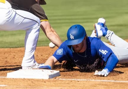 Los Angeles Dodgers base runner James Tibbs III dives back to first base on a pickoff attempt against the San Diego Padres during a spring training game at Peoria Sports Complex