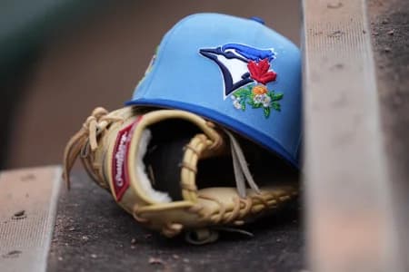 Detail photo. A Toronto Blue Jays hat and glove rest on the first base dugout steps at Roger Dean Chevrolet Stadium before the game against the Miami Marlins
