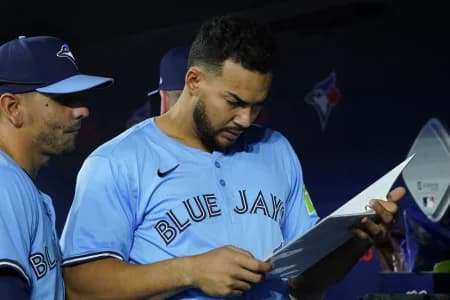 Toronto Blue Jays designated hitter Anthony Santander (25) and second baseman Andres Gimenez (0) review a playbook before a game against the Cleveland Guardians at Rogers Centre